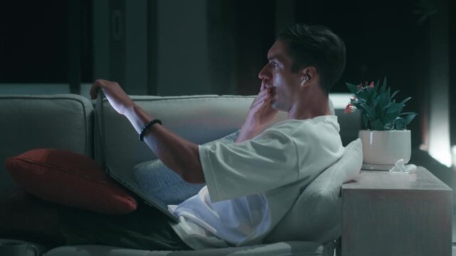 Man is shocked by terrible online news while working on laptop at night. Shock reaction shows panic fear crying despair and emotional trauma revealing mental stress from digital information.