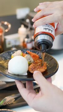 Pouring Sweet Chili Sauce Over Dim Sum and Fried Shrimp at Buffet