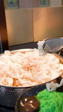 Person Using Metal Tongs to Serve Shrimp Crackers at Buffet