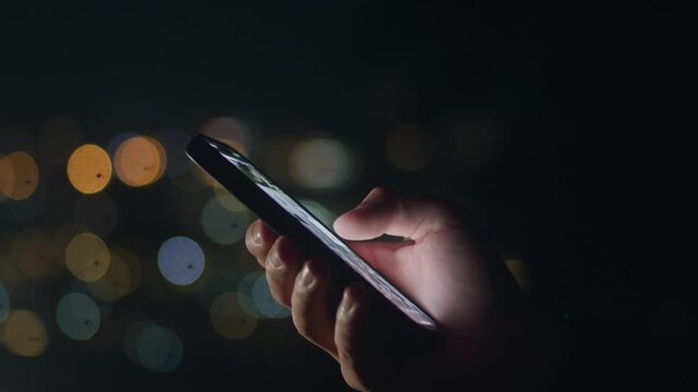 Male hand using smartphone at night and interacting with mobile screen. Mobile communication concept shows digital connection online messaging social media use and constant smartphone interaction.