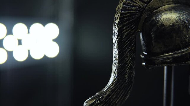 Macro rotating shot of ancient Spartan bronze helmet with water drops and dramatic studio lighting