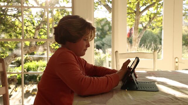 12 year old boy using tablet computer at home