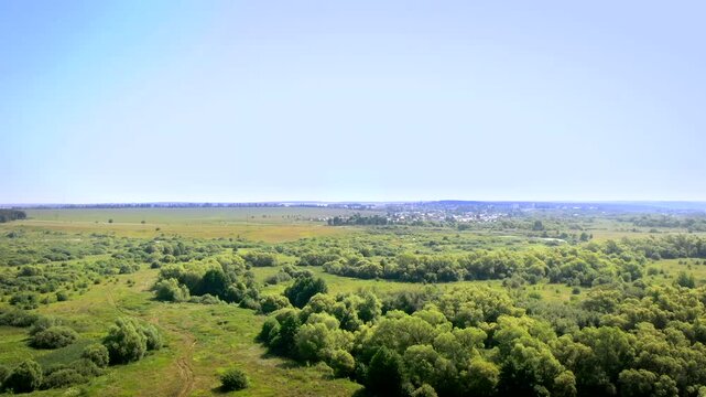 Expansive countryside landscape with patches of trees and open land seen from above in bright daylight.