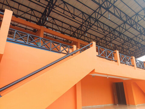 Entry stairs to tribune of stadium in Southeast Asia. 
Empty orange tribune with seats