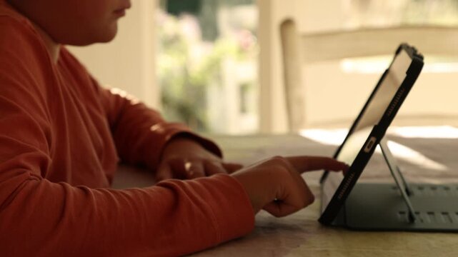 12 year old boy using tablet computer at home at sunset