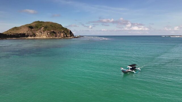 Aerial perspective captures a classic Indonesian jukung boat gracefully sailing through the breathtaking turquoise waters on a sunny day, surrounded by vibrant green islands in the distance