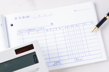 請求書 - 取引先に宛てた請求書を作成しているビジネスシーンのイメージ  © PJM