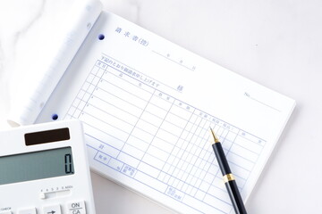 請求書 - 取引先に宛てた請求書を作成しているビジネスシーンのイメージ  © PJM
