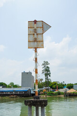 Fototapeta premium Rusty navigation marker with water background, vintage signpost, industrial waterfront scene, weathered metal, coastal environment, and serene view.