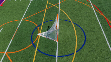 Aerial view of a multi-purpose athletic turf field featuring a lacrosse goal within a blue circular crease and overlapping colored lines for different sports.  Lacrosse, Soccer, Field Hockey, Football © Thomas