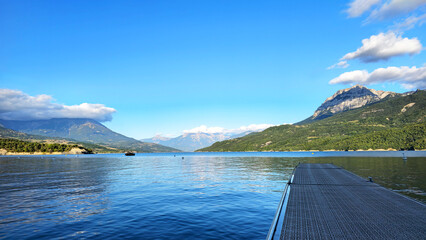Pier extending into Lac de Serre Poncon with mountains, Hautes Alpes, Alpes-de-Haute-Provence, France, Europe. © Iryna Shpulak