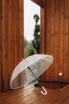 Transparent umbrella resting on wet wooden deck