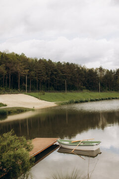 Rowboat tethered to pier on serene lake reflecting forest