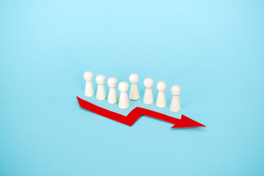 Line of wooden peg dolls stands behind red downward arrow on blue background. Corporate mass layoffs, rising unemployment rate, job market instability, Human resources crisis.
