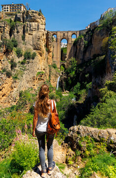 female traveler looking at puente nuevo stone bridge and waterfall in ronda spain