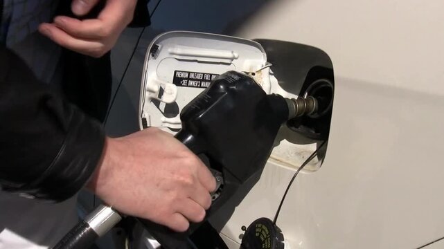 Refueling a car with fuel, Filling fuel into a car tank. driver refuels auto gas station for cars. The car's tank cap is open with diesel fuel economy