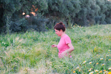 Naklejka premium woman among ears of wheat in the field