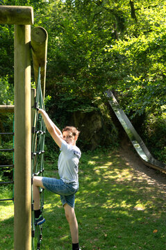 Child climbing playground structure outdoors in sunny park