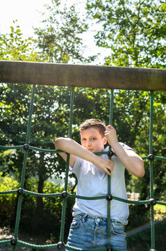 Boy climbing rope structure on playground in sunny park