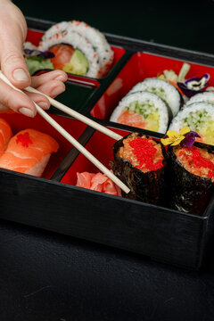 Girl eating Asian food from bento box with chopsticks