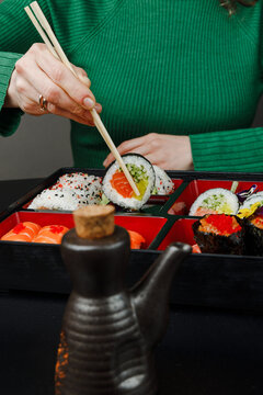 Girl eating Asian food from bento box with chopsticks