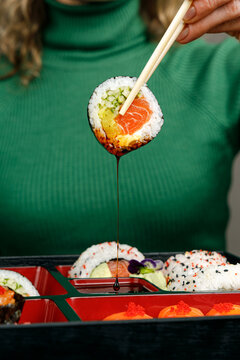 Girl eating Asian food from bento box with chopsticks