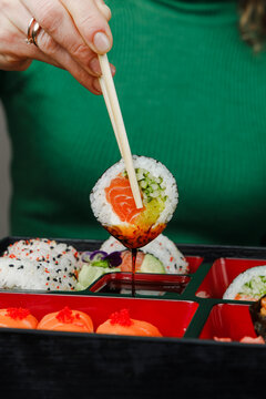 Girl eating Asian food from bento box with chopsticks