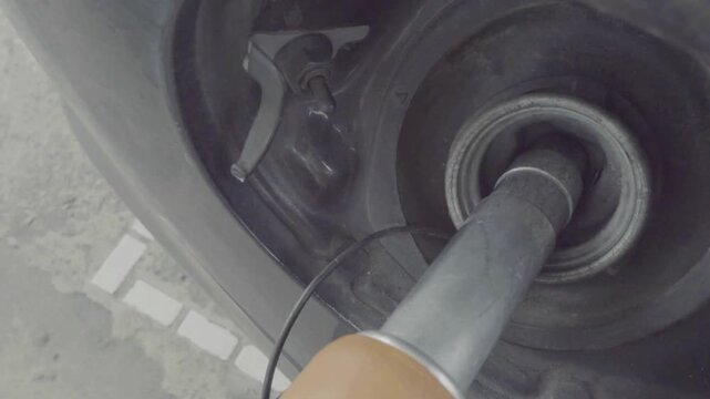 Fuel nozzle inserted in car's gas tank as it's being refueled at gas station pump. Fuel at gas station. diesel, gas station, petrol prices concept.