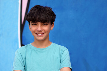 portrait of teenage boy smiling in front of a blue background with lighting is soft and natural. © Inspiraciones