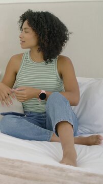 Vertical video: Reacting woman in striped tank talking on bed after yellow sleeve appearing, phone