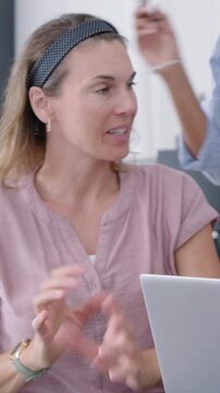 Vertical video: Looking at laptop woman in pink top leaning, pointing and explaining plan at home