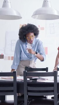 Vertical video: Leaning forward woman with glasses reviewing layouts at studio table with swatches