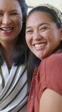 Vertical video: Camera moving, mom-daughter laughing leaning to lens at home with striped blouse