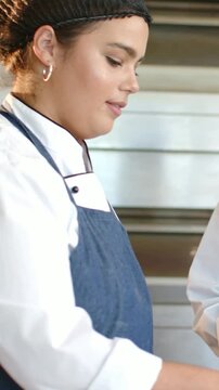 Vertical video: Glancing at dough, chef in blue apron shaping dough at prep counter to bake