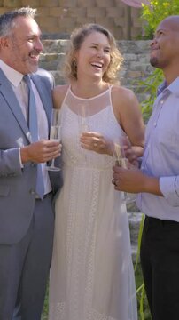 Vertical video: Toasting woman in lace dress raising flutes after laughter in garden, showing ring