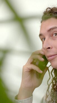 Vertical video: Answering call adult holding phone to ear at home listening with cuff near plant