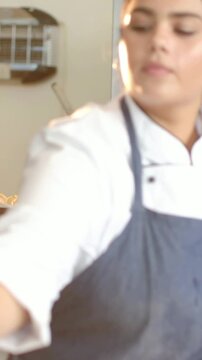 Vertical video: Reaching chef in chef coat, apron picking up small jar salting dish near oven rack