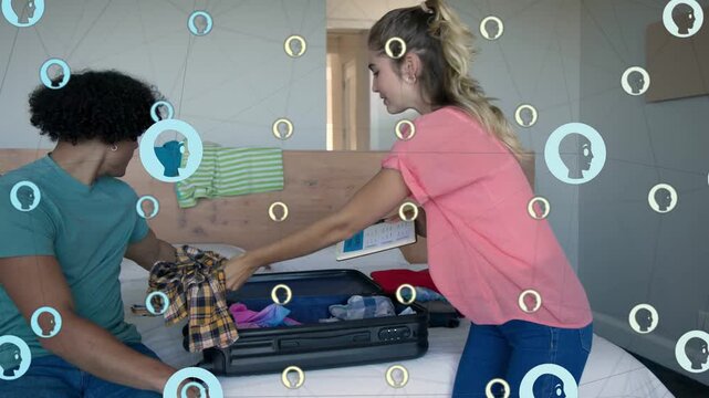 Man and woman packing suitcase on bed, woman handing shirt checking tablet, icons overlaying travel