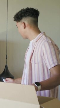 Vertical video: Opening box man in pink shirt lifting linen, walking to bedroom and preparing bed