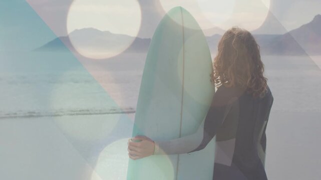 Woman holding mint board at shore, spotting waves, turning and preparing to surf, bokeh over frame