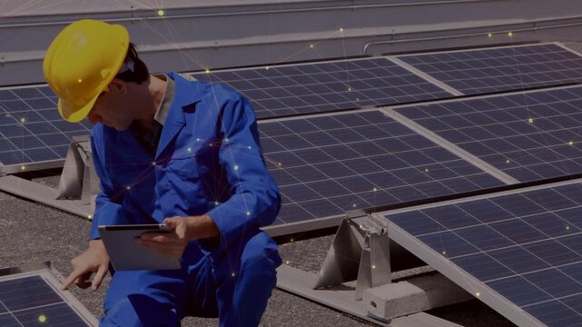 Tech kneeling by solar panels tapping tablet starting panel tests while glints appearing on panels