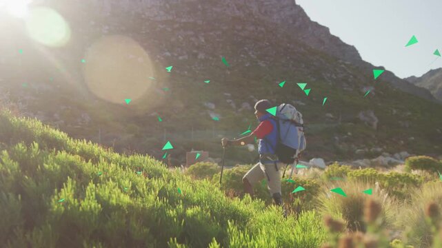 Male hiker pausing and checking map while ascending hiking trail, green triangles overlaying path
