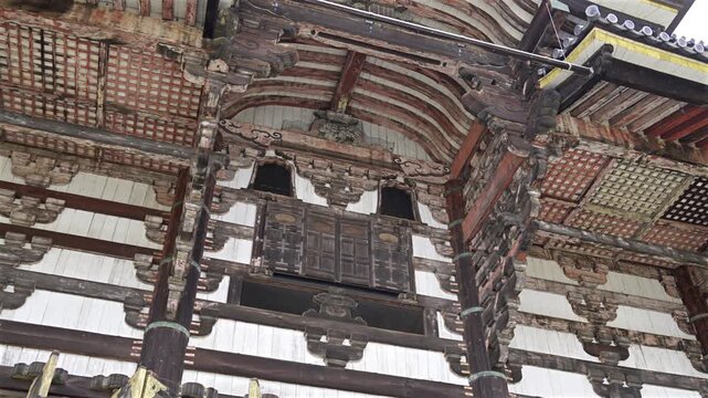 Ancient wooden beams and detailed carvings on historic building facade filmed from below.