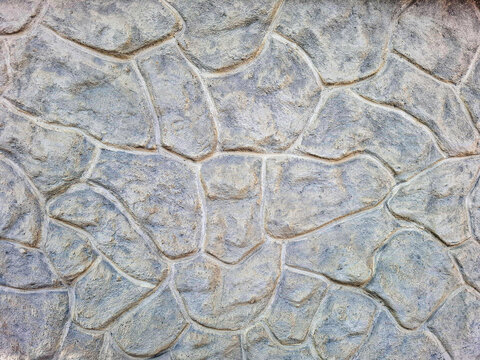 Textured stone wall with grey and beige flagstones fitted in rustic design for architectural use