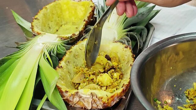 Preparing authentic Thai pineapple fried rice in a hollowed pineapple shell.