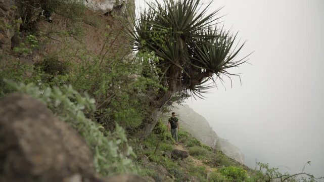 Static Shot of Tourist at Jebel Samhan Overlook, Cinematic Male Traveler Above Rolling Clouds and Fog in Salalah Oman