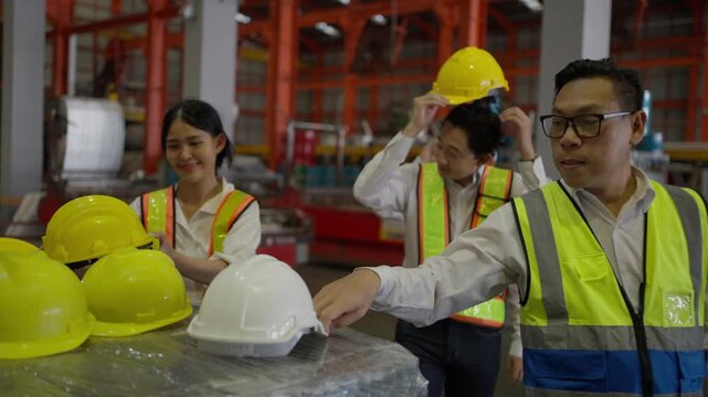 Industrial worker wearing safety helmet and reflective vest while working inside manufacturing factory environment.