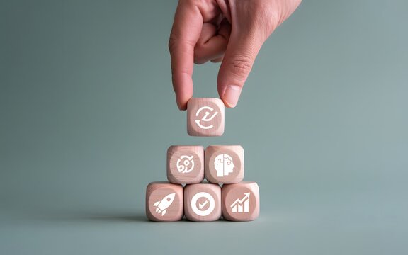 Minimalist photograph of a hand placing an iterative process cube atop a strategic business pyramid, symbolizing continuous improvement and development