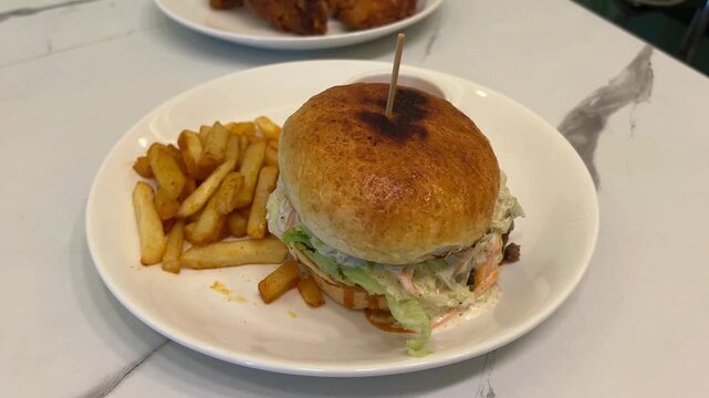 American-style Nashville chicken burger and fries; professional food photography of a spicy fried chicken burger combo meal prepared in a modern restaurant setting in India.