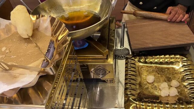 Culinary traditions of India: A professional cook deep-frying fresh, puffed bread in a traditional kadhai at an interactive live counter during a luxury wedding banquet.